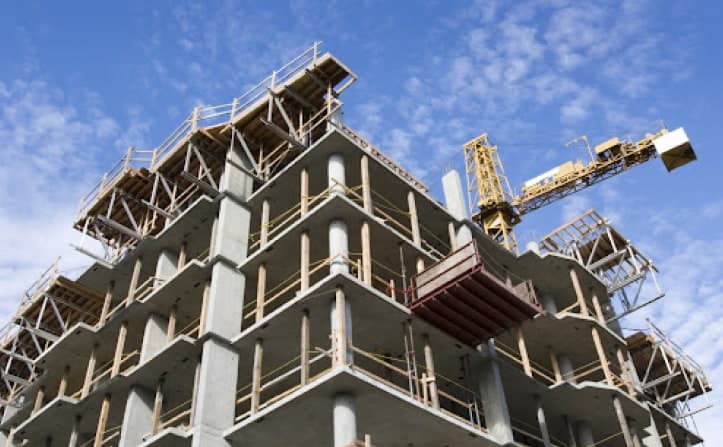 Concrete building structure with scaffolding and a crane against the sky